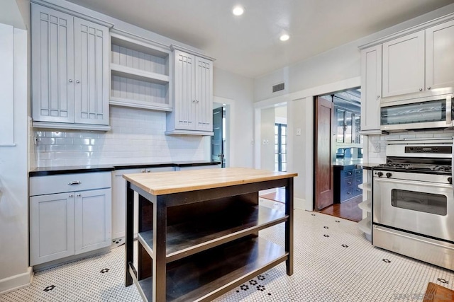 kitchen with gray cabinetry, light tile patterned floors, appliances with stainless steel finishes, tasteful backsplash, and butcher block counters