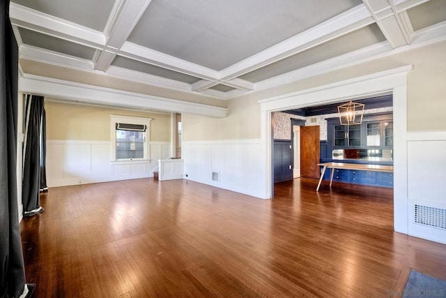 unfurnished living room with beam ceiling, dark wood-type flooring, coffered ceiling, and a notable chandelier