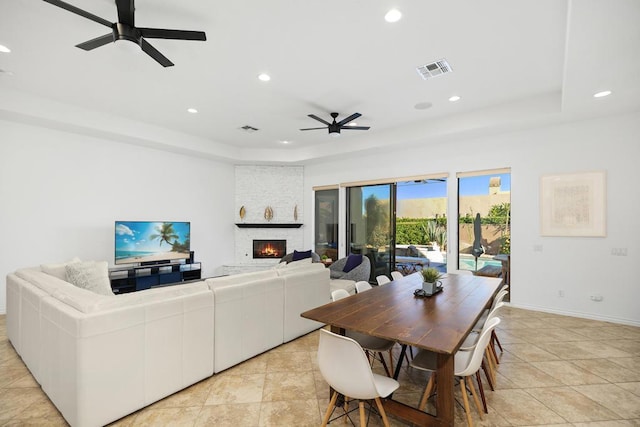 dining area featuring a fireplace, light tile patterned floors, and ceiling fan