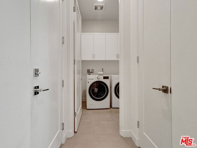 washroom featuring cabinets, light tile patterned floors, and washing machine and dryer