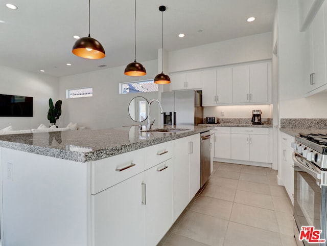 kitchen with appliances with stainless steel finishes, sink, a center island with sink, white cabinets, and hanging light fixtures