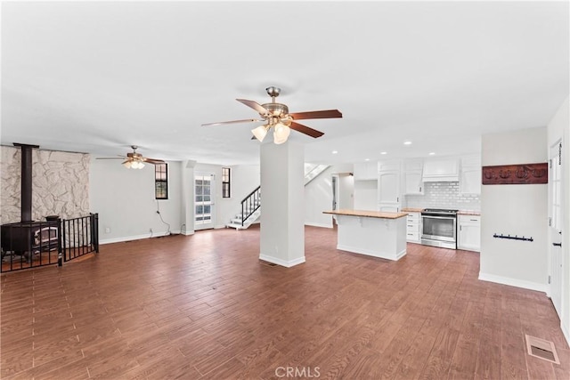 unfurnished living room with a wood stove, ceiling fan, and hardwood / wood-style floors