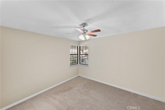 empty room featuring ceiling fan, light colored carpet, and a textured ceiling