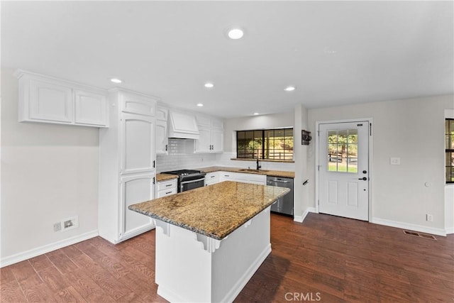 kitchen with white cabinets, custom range hood, sink, and appliances with stainless steel finishes