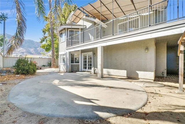 back of house with a mountain view, a balcony, a patio, and french doors