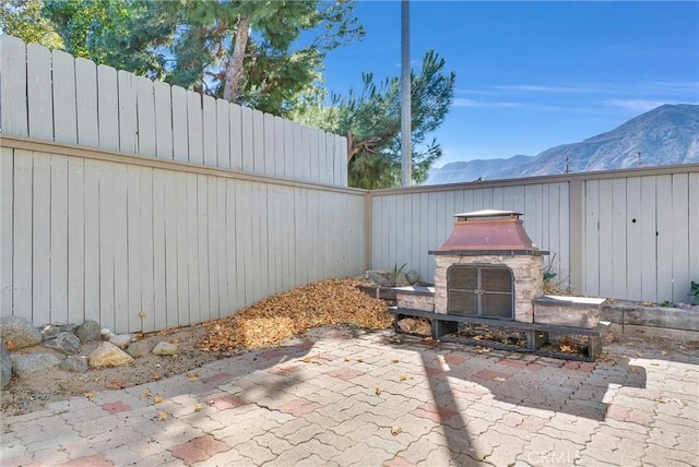 view of patio / terrace with a mountain view and an outdoor stone fireplace