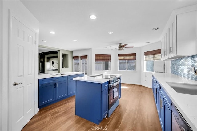 kitchen featuring blue cabinetry, sink, a center island, wood-type flooring, and appliances with stainless steel finishes