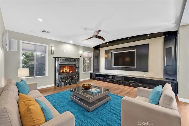 living room featuring ceiling fan, plenty of natural light, a high end fireplace, and hardwood / wood-style floors