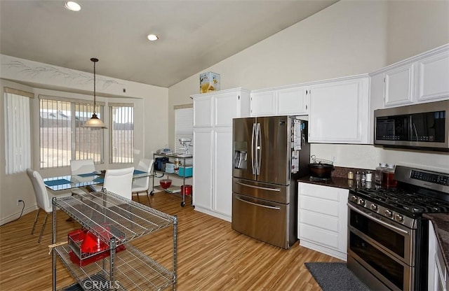 kitchen featuring vaulted ceiling, appliances with stainless steel finishes, pendant lighting, light hardwood / wood-style floors, and white cabinets