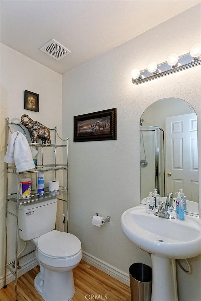 bathroom with hardwood / wood-style flooring, toilet, and walk in shower