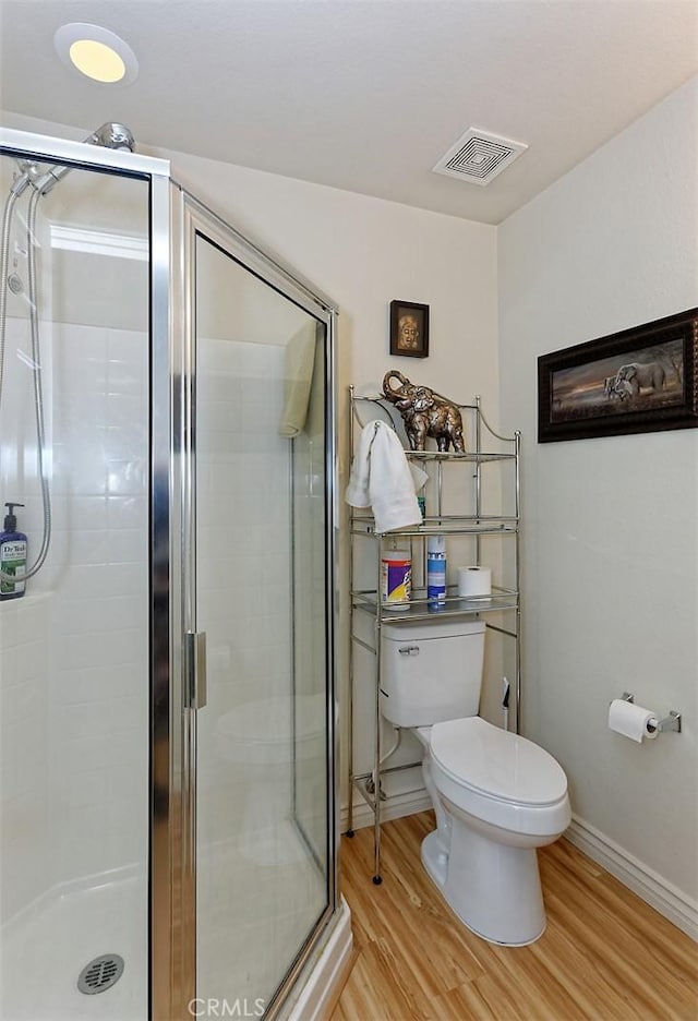 bathroom with toilet, an enclosed shower, and hardwood / wood-style floors