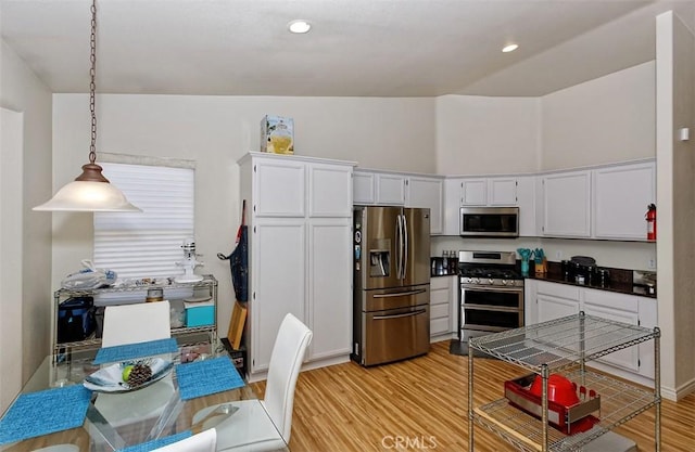 kitchen with white cabinetry, stainless steel appliances, light hardwood / wood-style floors, and hanging light fixtures