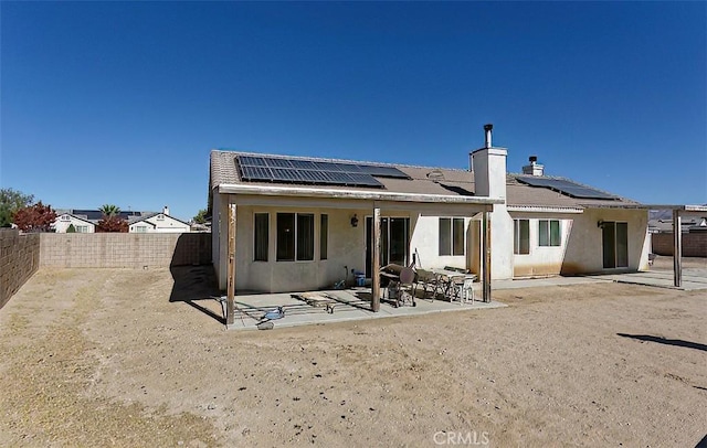 rear view of house with a patio and solar panels