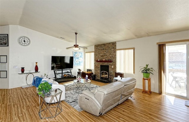 living room featuring wood-type flooring, lofted ceiling, ceiling fan, and a fireplace