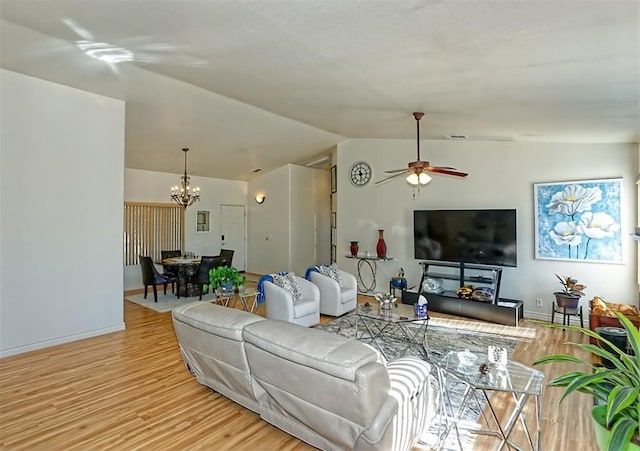 living room featuring ceiling fan with notable chandelier, vaulted ceiling, and light hardwood / wood-style floors