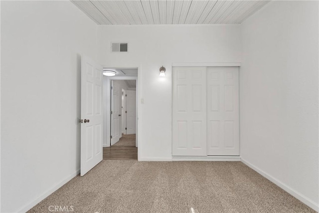 unfurnished bedroom featuring carpet floors, a closet, visible vents, and baseboards