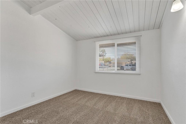 carpeted spare room featuring lofted ceiling with beams and baseboards