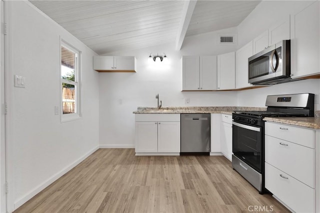 kitchen with white cabinets, appliances with stainless steel finishes, vaulted ceiling with beams, and light hardwood / wood-style floors