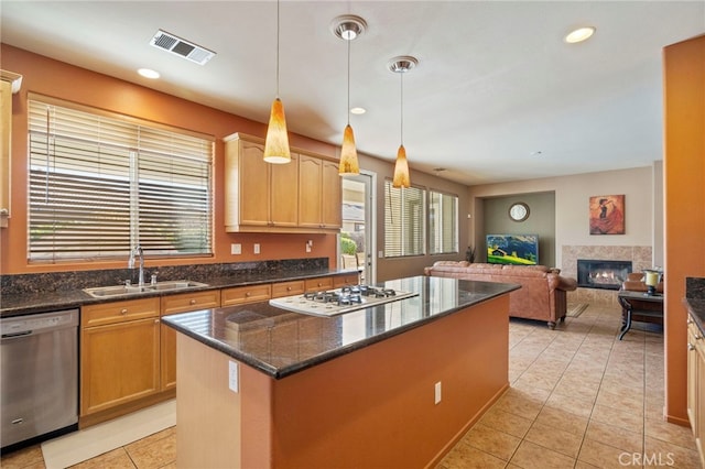 kitchen featuring dishwasher, a center island, sink, white gas stovetop, and a tiled fireplace