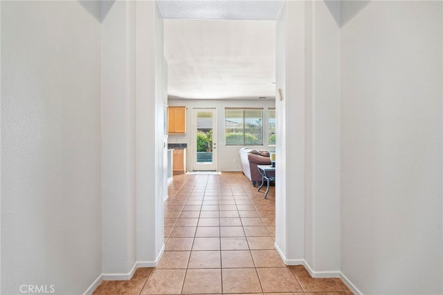 hallway with light tile patterned floors and baseboards