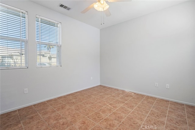 spare room with baseboards, visible vents, and ceiling fan