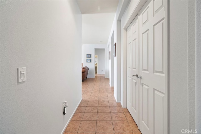 corridor with light tile patterned floors and baseboards