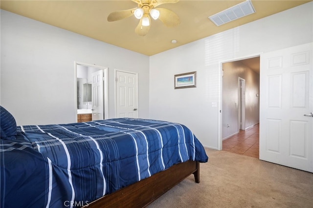 carpeted bedroom with tile patterned floors, visible vents, a ceiling fan, ensuite bath, and baseboards