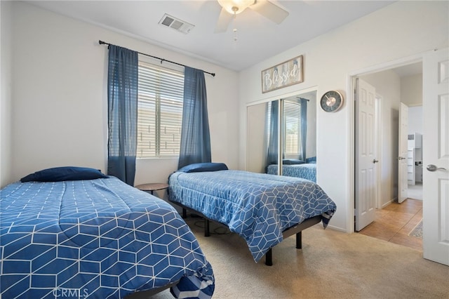 bedroom featuring a ceiling fan, visible vents, tile patterned flooring, a closet, and carpet flooring