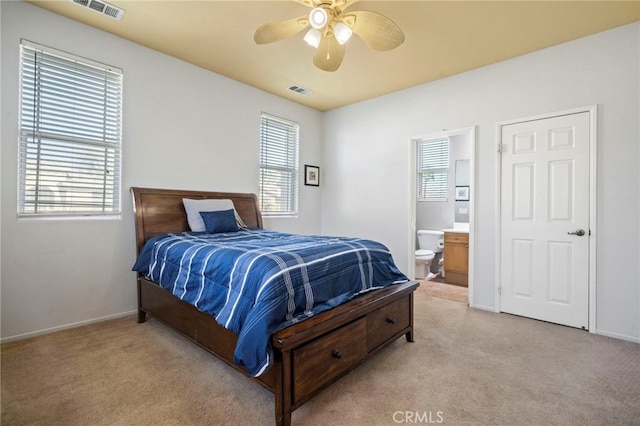 bedroom with visible vents, light colored carpet, connected bathroom, and baseboards
