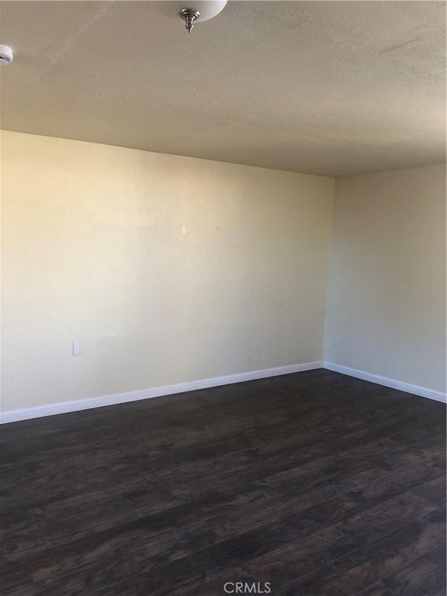 spare room featuring a textured ceiling and dark hardwood / wood-style floors