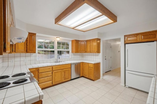 kitchen featuring sink, tile counters, white appliances, range hood, and backsplash