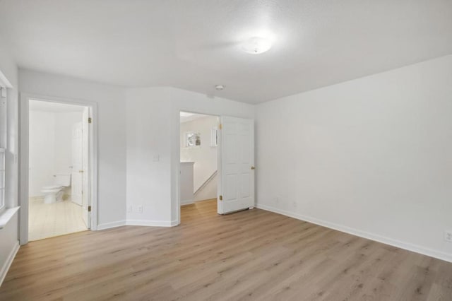 unfurnished bedroom featuring connected bathroom and light hardwood / wood-style flooring