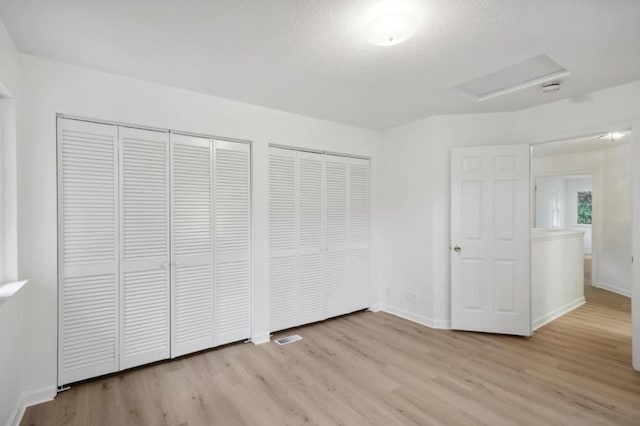 unfurnished bedroom featuring two closets and light hardwood / wood-style floors