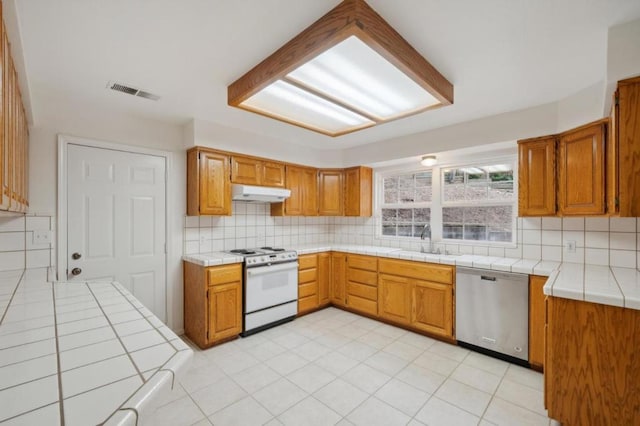 kitchen with stainless steel dishwasher, tile countertops, sink, and electric range