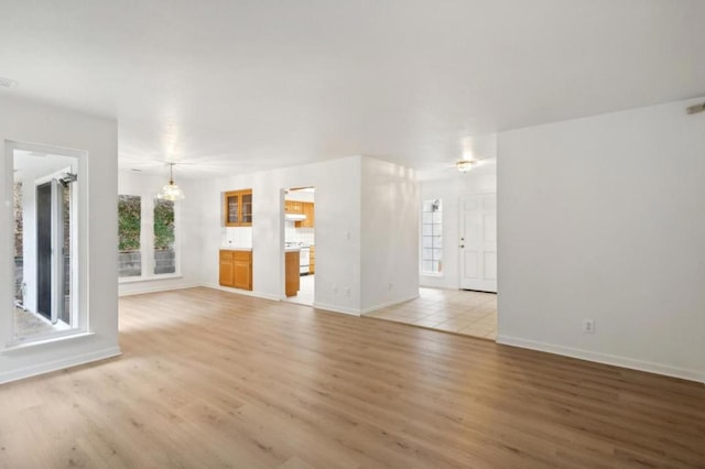 unfurnished living room featuring a chandelier and light hardwood / wood-style floors