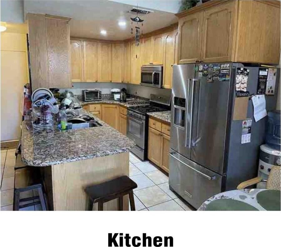 kitchen with a kitchen breakfast bar, dark stone countertops, light tile patterned floors, and appliances with stainless steel finishes