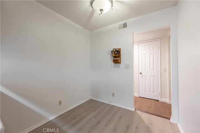 empty room with light hardwood / wood-style flooring and a textured ceiling