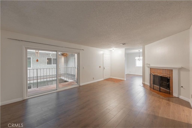 unfurnished living room featuring a tile fireplace, wood-type flooring, and a textured ceiling