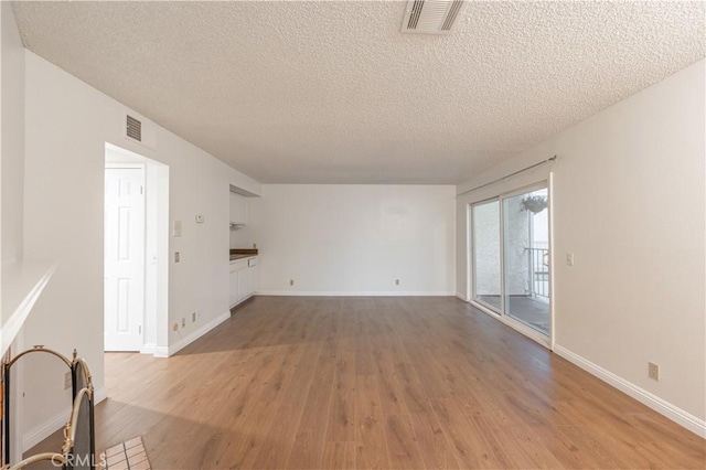 unfurnished living room featuring light hardwood / wood-style flooring and a textured ceiling