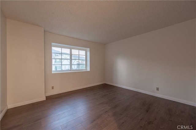 empty room featuring a textured ceiling and dark hardwood / wood-style flooring