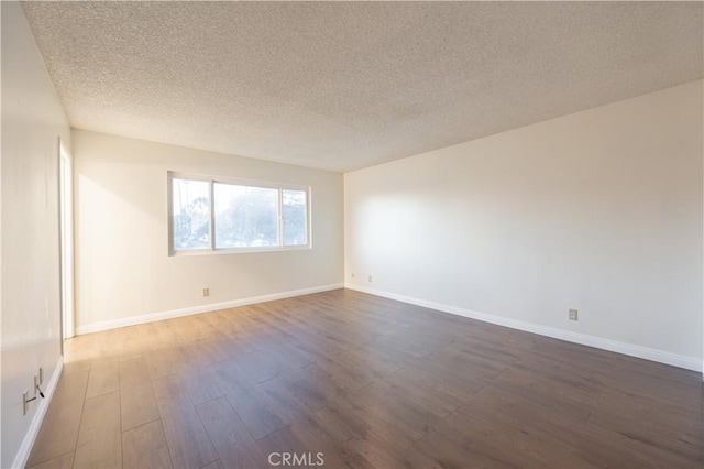 empty room with a textured ceiling and dark wood-type flooring