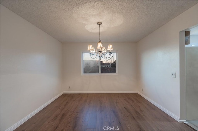 unfurnished dining area featuring a textured ceiling, dark wood-type flooring, and a chandelier