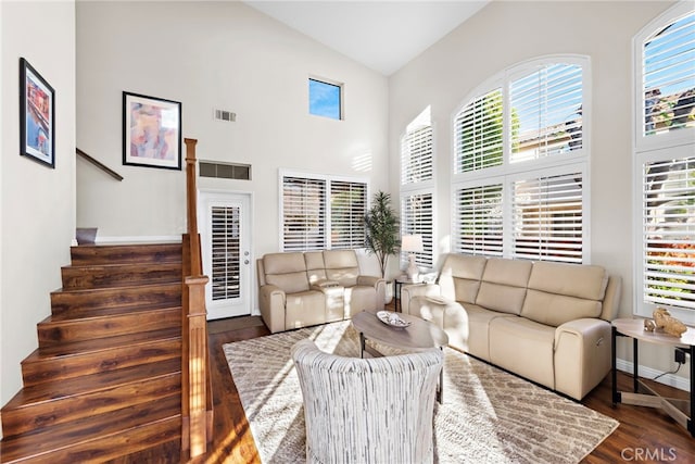 living area featuring visible vents, high vaulted ceiling, wood finished floors, baseboards, and stairs