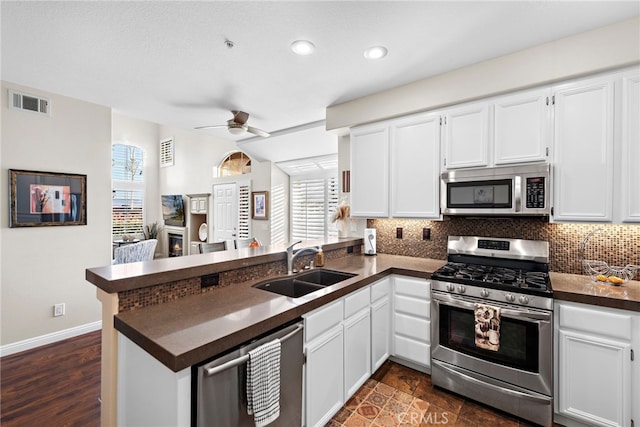 kitchen with dark countertops, visible vents, backsplash, appliances with stainless steel finishes, and a peninsula