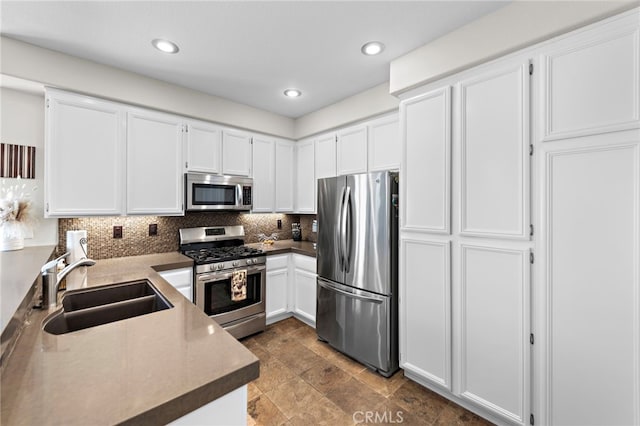 kitchen with recessed lighting, a sink, decorative backsplash, appliances with stainless steel finishes, and white cabinetry