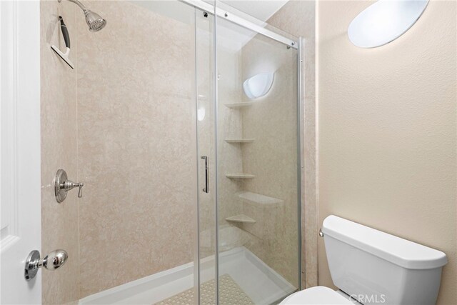 bathroom with a shower with shower door and toilet