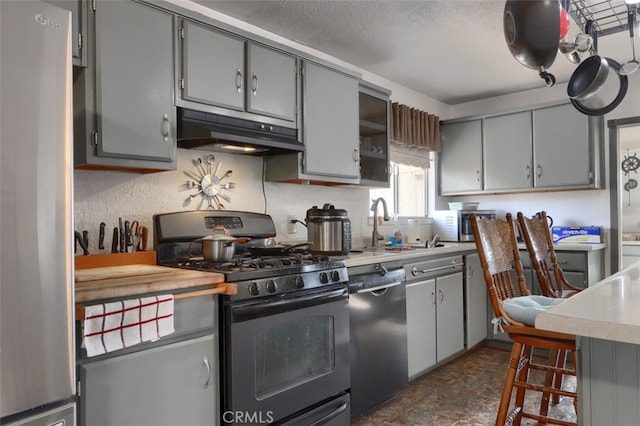 kitchen featuring gray cabinets, a textured ceiling, and appliances with stainless steel finishes