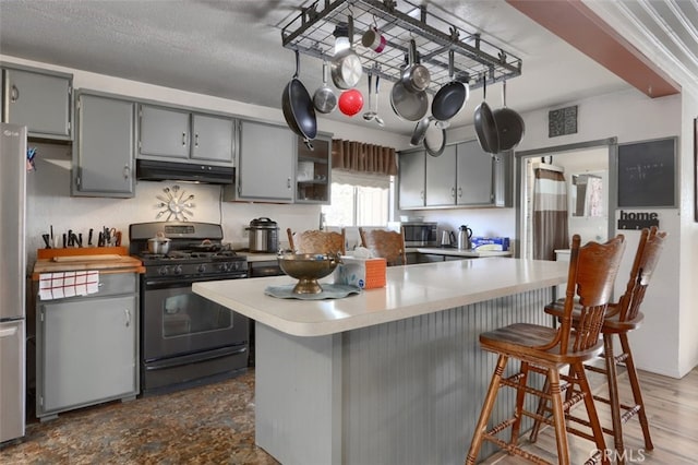 kitchen featuring gray cabinetry, a kitchen breakfast bar, stainless steel appliances, and hardwood / wood-style flooring