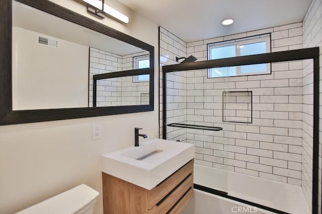 full bathroom featuring combined bath / shower with glass door, vanity, and toilet