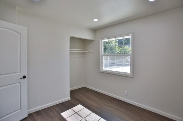 unfurnished bedroom with dark hardwood / wood-style flooring and a closet